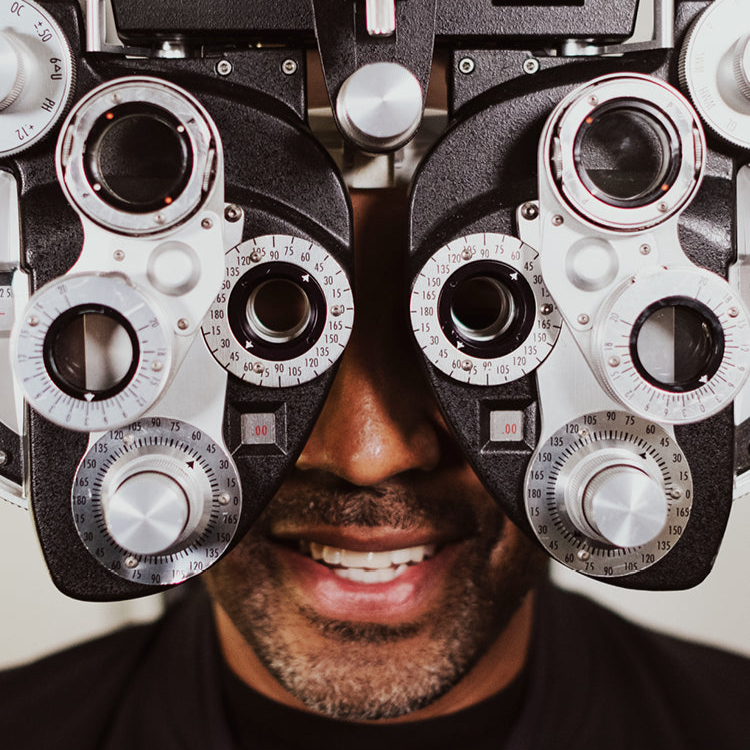 A close up of a man getting an eye exam. He is behind an eye calibration machine.
